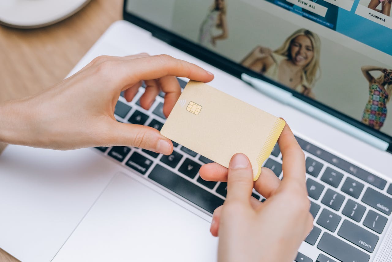 Close-up of hands holding credit card for online shopping on a laptop. Perfect for e-commerce and finance visuals.